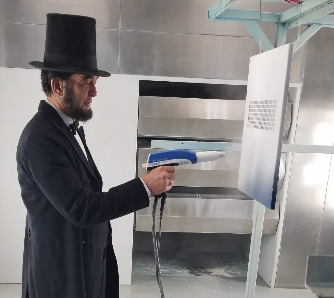 A man dressed as Abraham Lincoln using a powder coating gun